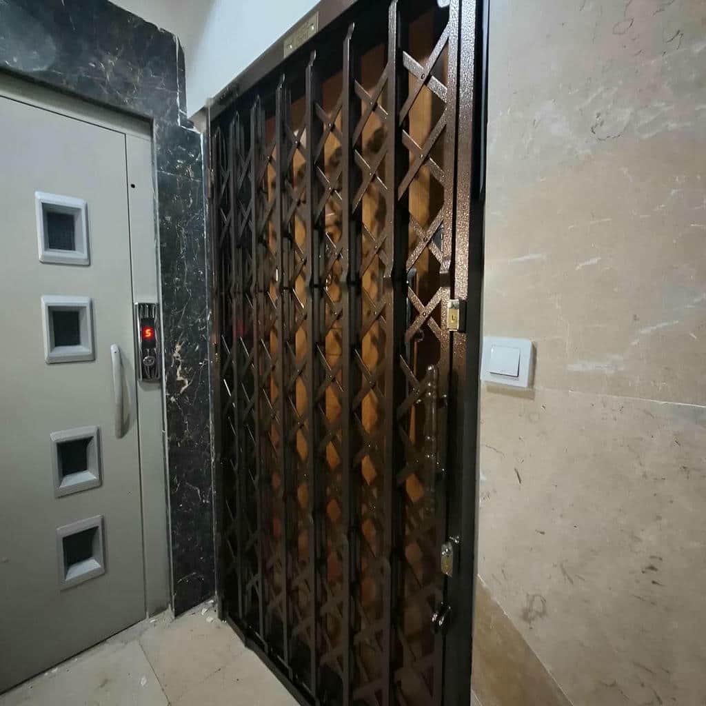 حفاظ درب آکاردئونی جمع شده کنار درب آپارتمان