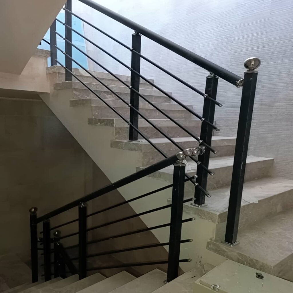 نرده راه پله استیل کنار پله سنگی با نور طبیعی